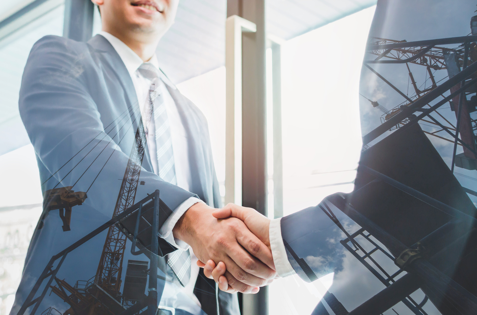 Two business men shaking hands in front of a modern office building